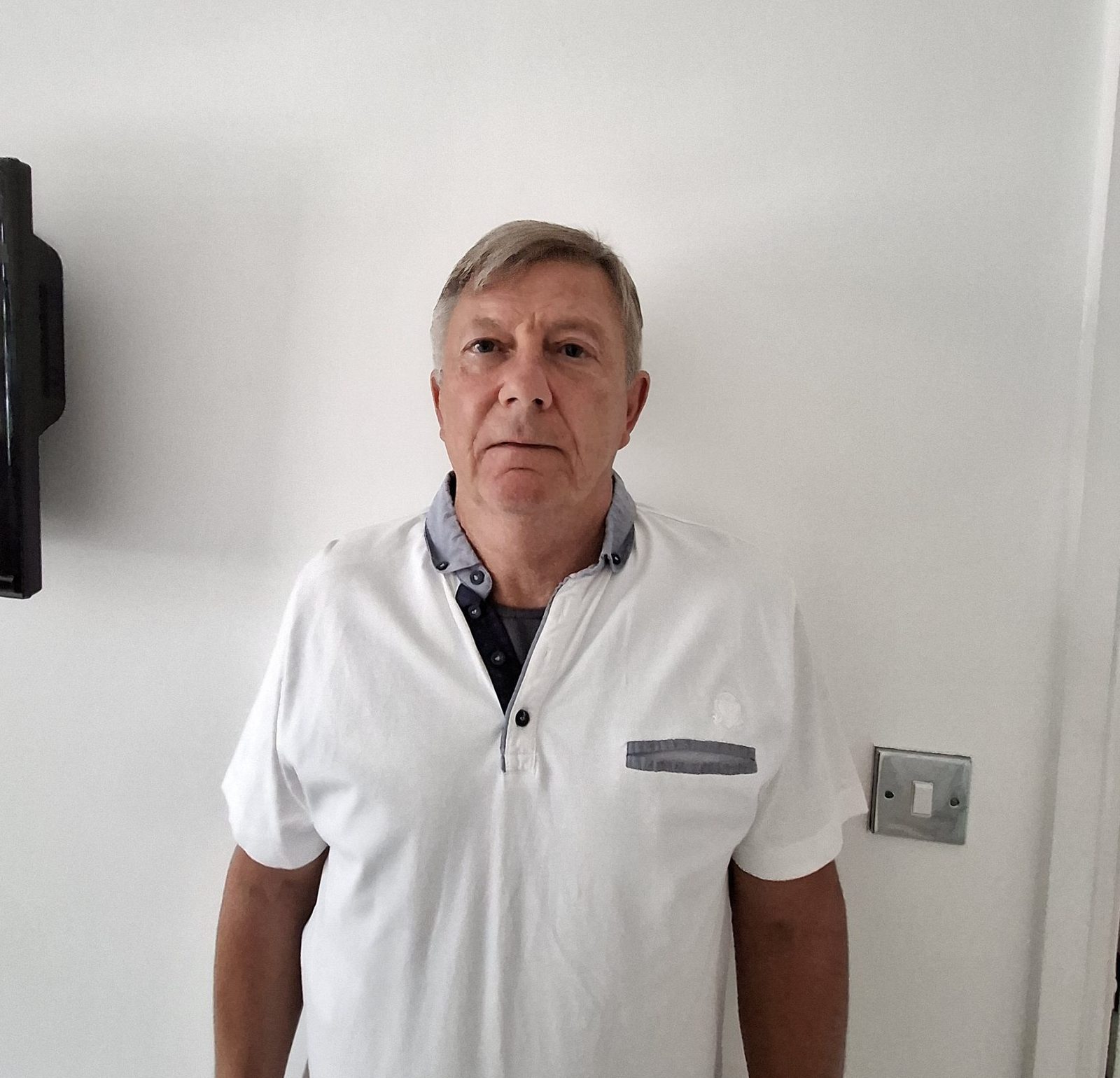 A picture of Cllr Chris Grubb. Chris wears a white top with blue collar. The image background is white.