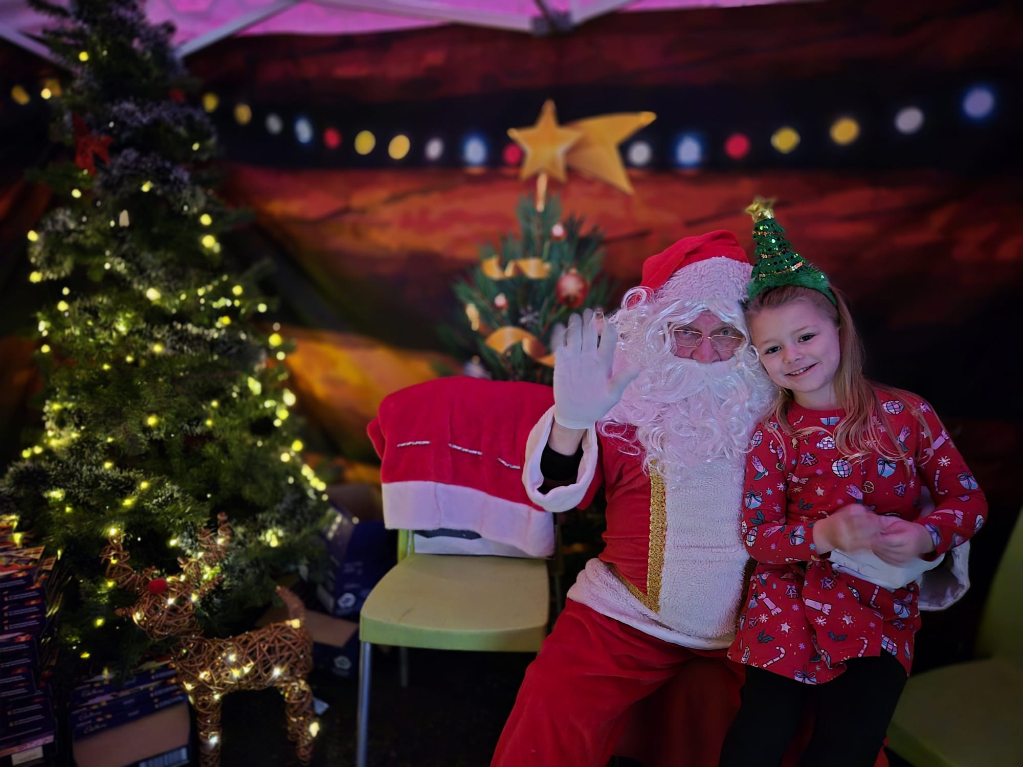 An image of Santa Claus in his grotto with a young girl in a festive dress.
