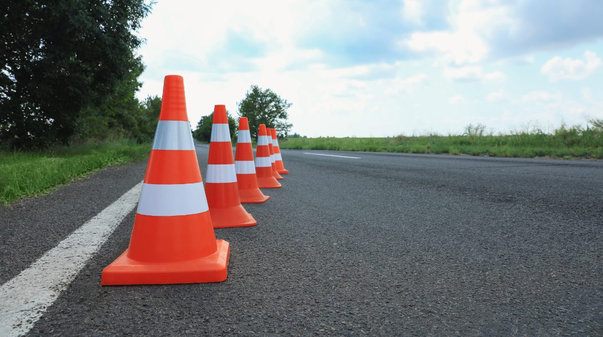 An image featuring traffic cones lined up on a country road.